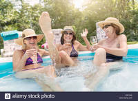 photo of mature women comp yyk three mature women sitting paddling pool drinking wine stock photo